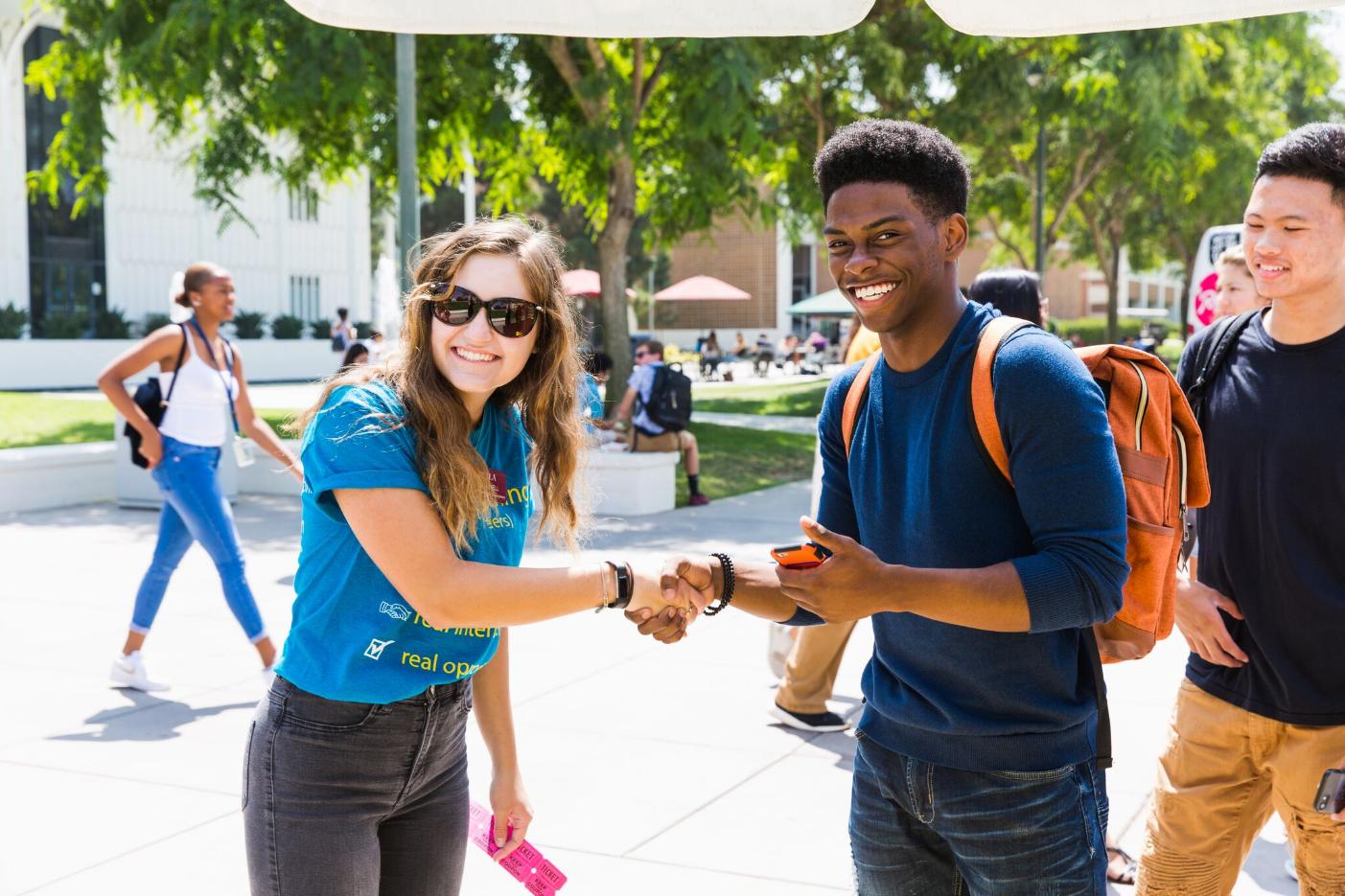 Two students shaking hands on Alumni Mall.